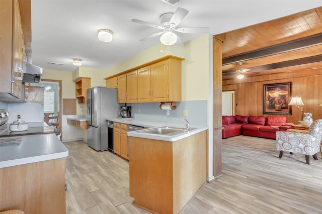 kitchen with sink, light hardwood / wood-style flooring, wooden walls, ceiling fan, and stove