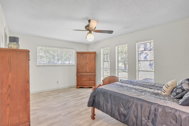 bedroom with ceiling fan, light hardwood / wood-style floors, and a textured ceiling