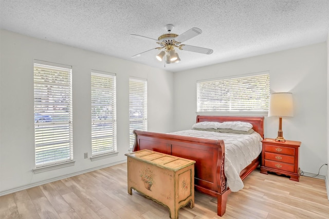 bedroom featuring multiple windows, a textured ceiling, ceiling fan, and light hardwood / wood-style flooring