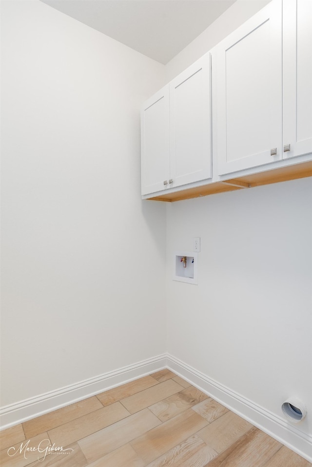 laundry room with washer hookup, light hardwood / wood-style floors, and cabinets