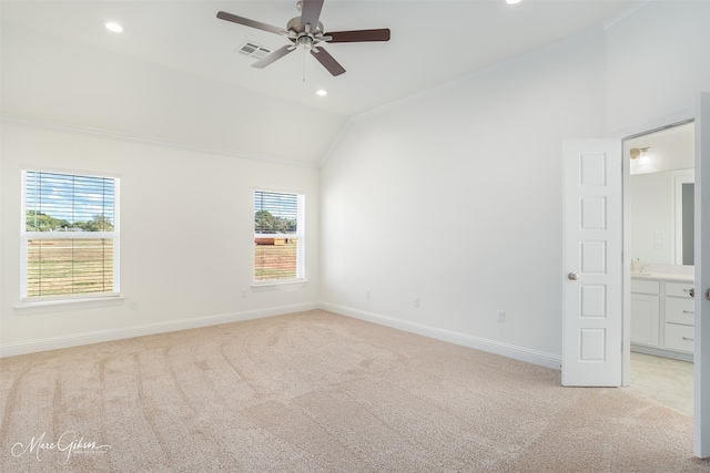 carpeted empty room with ornamental molding, vaulted ceiling, ceiling fan, and plenty of natural light