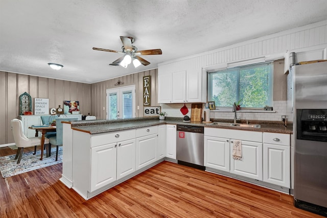 kitchen featuring white cabinets, kitchen peninsula, stainless steel appliances, and light hardwood / wood-style floors