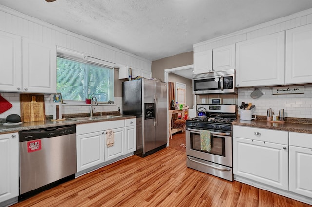 kitchen featuring backsplash, white cabinetry, light wood-type flooring, sink, and stainless steel appliances