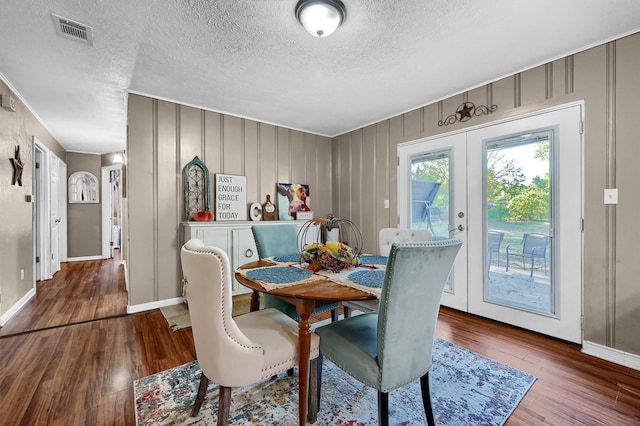 dining space featuring french doors, wood-type flooring, and a textured ceiling