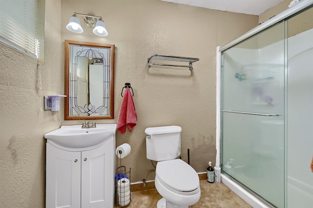 bathroom featuring vanity, toilet, and a shower with shower door