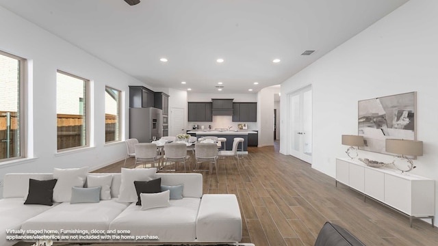 living room with recessed lighting, visible vents, baseboards, and wood finished floors