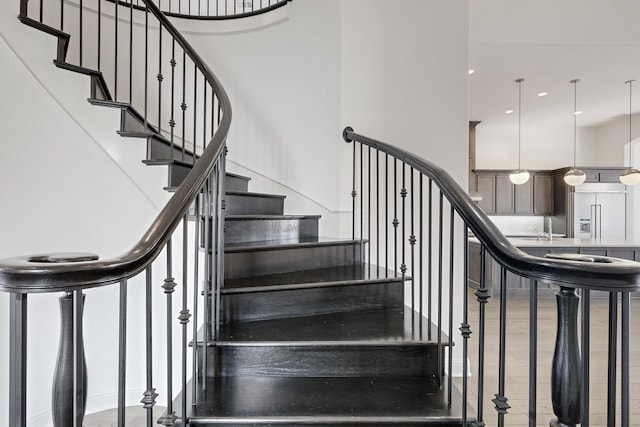 stairs featuring hardwood / wood-style flooring, sink, and a high ceiling