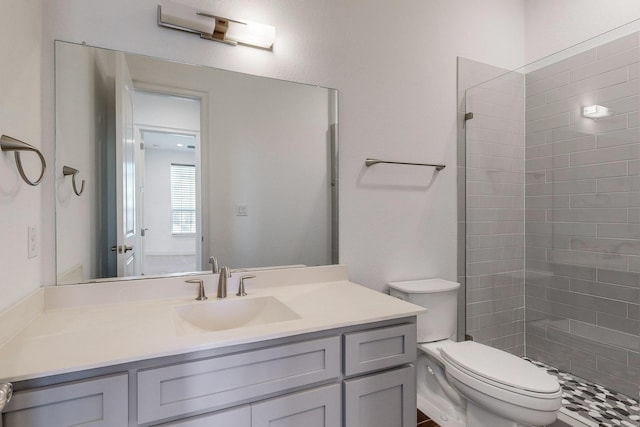 bathroom with vanity, toilet, and a tile shower