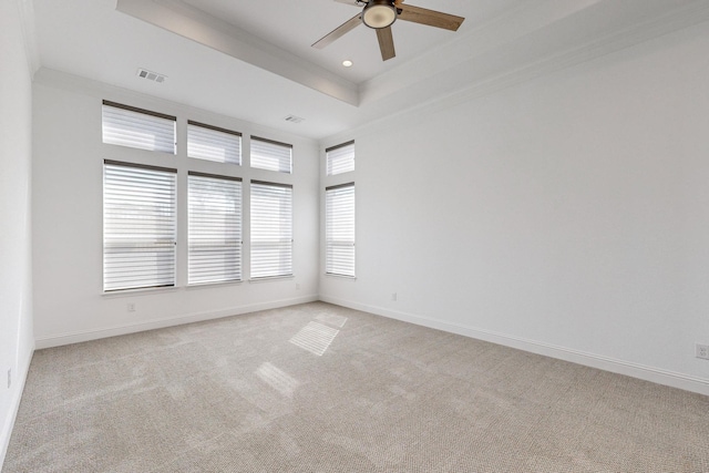 empty room with crown molding, light carpet, ceiling fan, and a tray ceiling