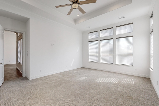 carpeted empty room featuring a tray ceiling, ornamental molding, and ceiling fan