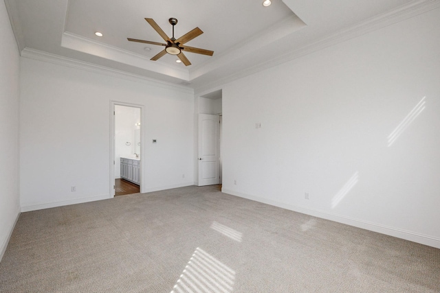 unfurnished bedroom with crown molding, ceiling fan, ensuite bathroom, a tray ceiling, and carpet floors