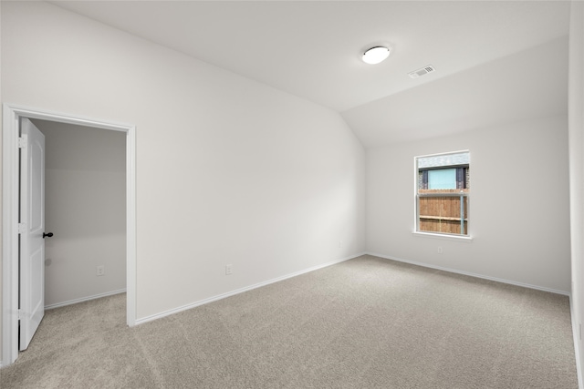 spare room featuring vaulted ceiling and light colored carpet