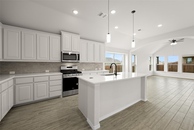 kitchen with white cabinets, appliances with stainless steel finishes, lofted ceiling, and sink