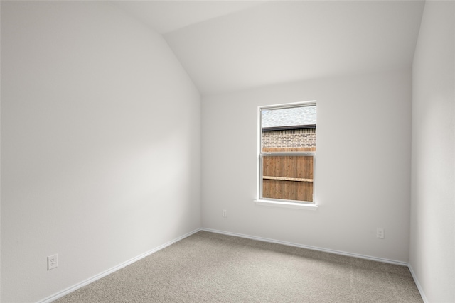 carpeted empty room with vaulted ceiling