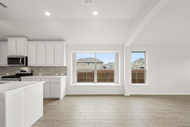 kitchen featuring white cabinets, appliances with stainless steel finishes, light wood-type flooring, and decorative backsplash