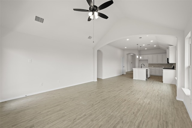 unfurnished living room featuring sink, high vaulted ceiling, light hardwood / wood-style floors, and ceiling fan