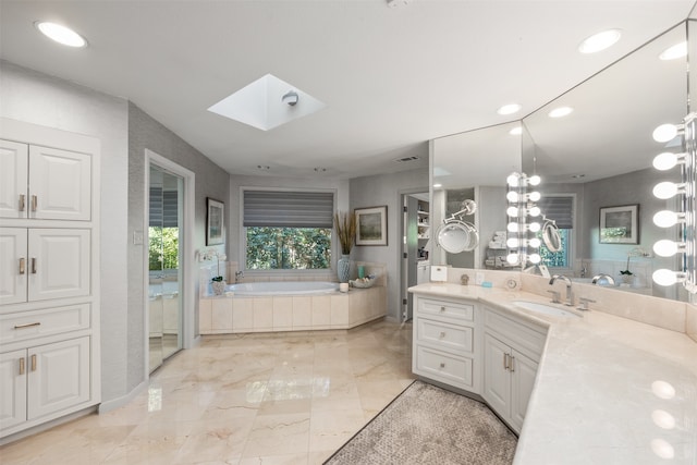 bathroom with vanity, a skylight, and a washtub