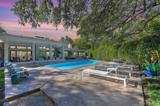 pool at dusk featuring a patio