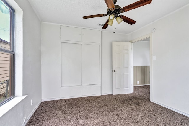 unfurnished bedroom featuring carpet flooring, multiple windows, and ceiling fan