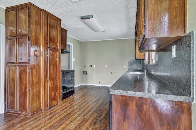 kitchen featuring a textured ceiling, ornamental molding, dark wood-type flooring, black range oven, and sink