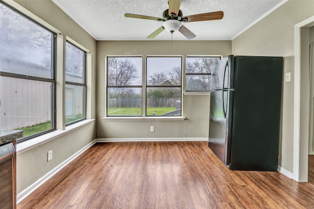 interior space with a textured ceiling, a healthy amount of sunlight, black refrigerator, and dark hardwood / wood-style flooring