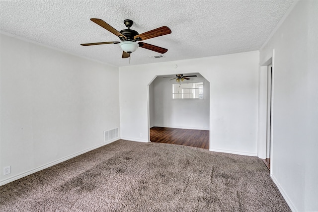 spare room featuring a textured ceiling, ceiling fan, and dark colored carpet