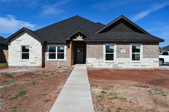 view of front of home with roof with shingles and brick siding