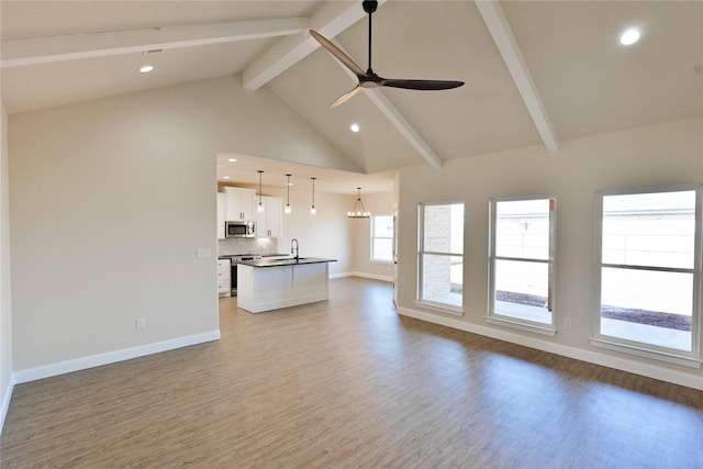 unfurnished living room with baseboards, beamed ceiling, wood finished floors, high vaulted ceiling, and ceiling fan with notable chandelier