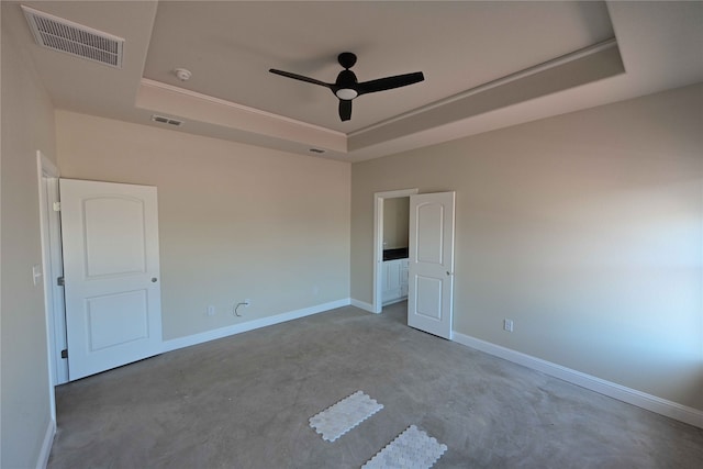 spare room with ceiling fan and a raised ceiling