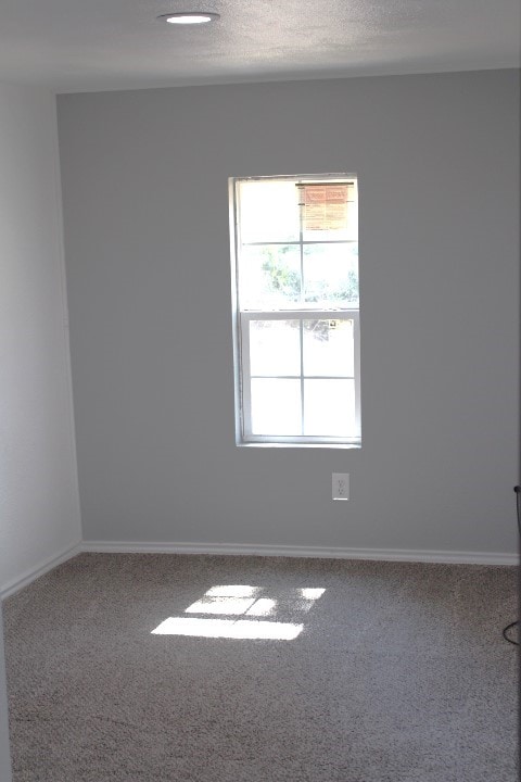 carpeted empty room featuring a textured ceiling