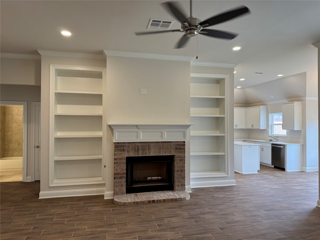 unfurnished living room featuring dark wood-type flooring, a brick fireplace, crown molding, and built in features