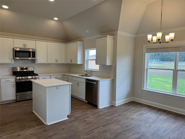 kitchen featuring appliances with stainless steel finishes, white cabinets, hanging light fixtures, and vaulted ceiling