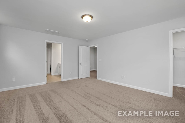 unfurnished bedroom featuring carpet flooring, a spacious closet, and a closet