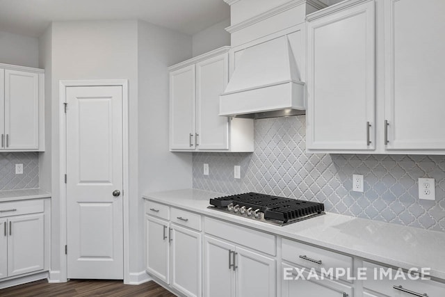 kitchen featuring dark hardwood / wood-style flooring, backsplash, custom range hood, stainless steel gas cooktop, and white cabinetry