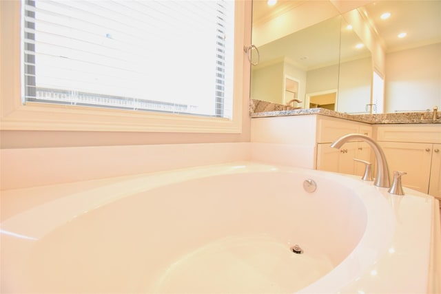 bathroom featuring vanity, a bath, ornamental molding, and a healthy amount of sunlight