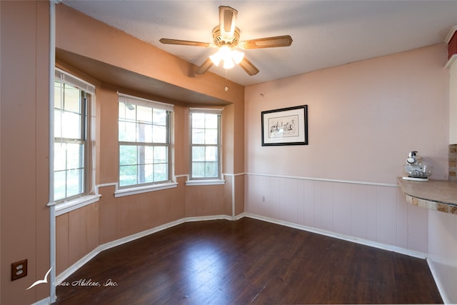 spare room with a textured ceiling, a healthy amount of sunlight, dark wood-type flooring, and ceiling fan