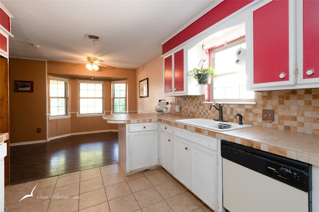 kitchen featuring kitchen peninsula, white dishwasher, sink, light hardwood / wood-style floors, and tasteful backsplash