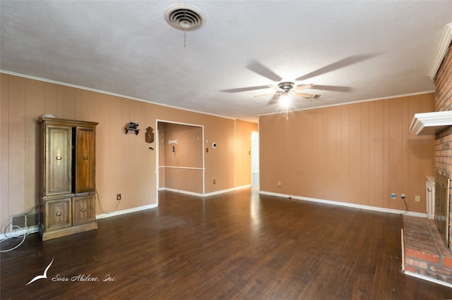 unfurnished living room with crown molding, wood walls, a brick fireplace, and dark hardwood / wood-style floors