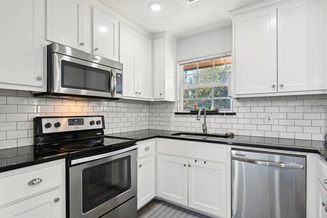 kitchen featuring sink, white cabinetry, appliances with stainless steel finishes, a textured ceiling, and tasteful backsplash