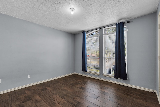 spare room featuring dark wood-type flooring and a textured ceiling