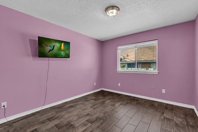 spare room with a textured ceiling and dark hardwood / wood-style floors