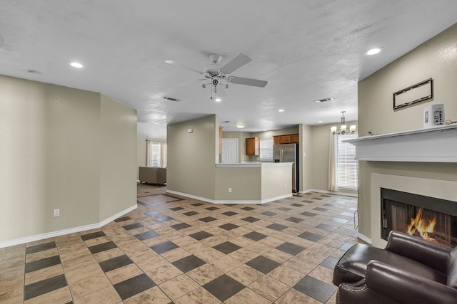 tiled living room featuring a healthy amount of sunlight and ceiling fan with notable chandelier