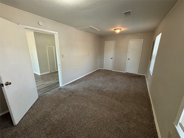 spare room with a textured ceiling and dark carpet