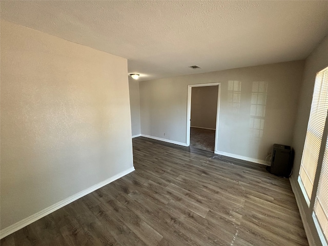 empty room with dark wood-type flooring and a textured ceiling