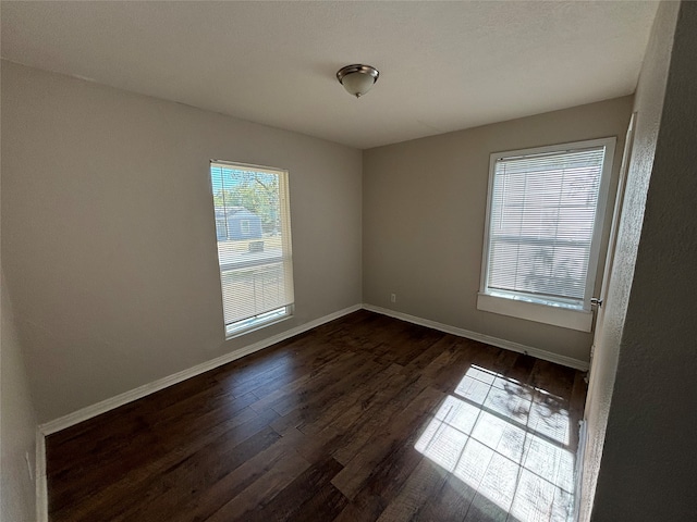 empty room with a wealth of natural light and dark hardwood / wood-style flooring