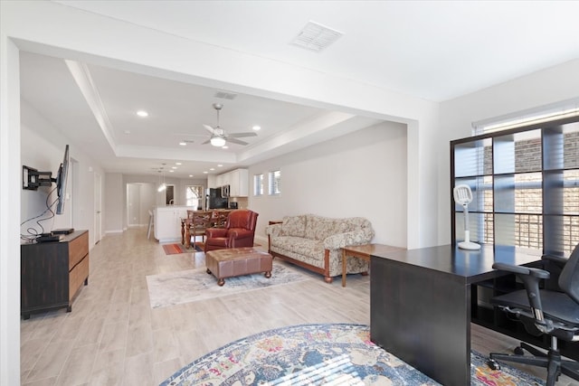 living room featuring plenty of natural light, ceiling fan, light hardwood / wood-style floors, and a raised ceiling