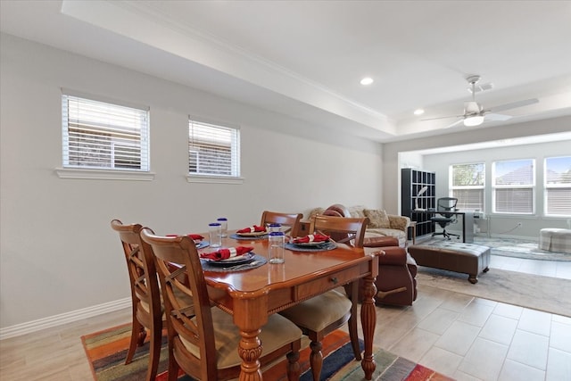 dining area with ornamental molding, light hardwood / wood-style floors, ceiling fan, and a raised ceiling