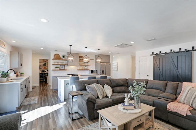 living room with a barn door, sink, and hardwood / wood-style floors