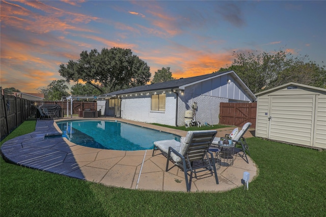 pool at dusk with a shed, a patio, and a yard