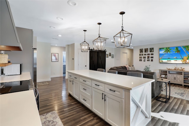 kitchen featuring hanging light fixtures, dark hardwood / wood-style floors, white cabinets, and a center island